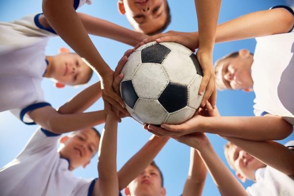 Jugendliche mit einem Fußball in der Hand als Symbolbild für das Thema Breitensport
