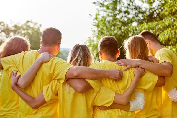 Sechs jugendliche Mitglieder eines Vereins in gelben T-Shirts halten sich gegenseitig an den Schultern