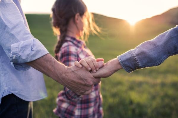 Eine junge Familie in der Natur hält sich an den Händen