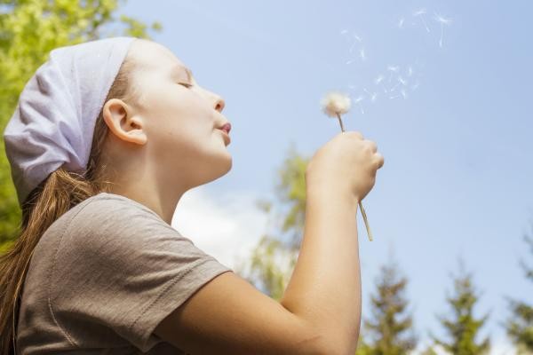 Ein Kind mit einer Pusteblume in der Hand