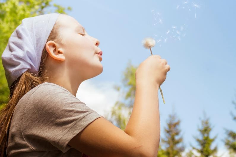 Kind mit einer Pusteblume in der Hand