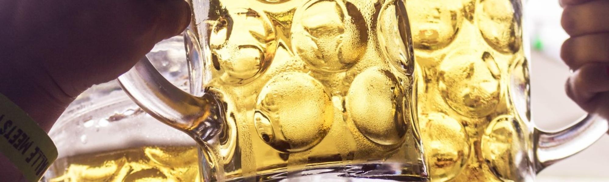 Bierkrüge als Symbolbild für die Rubrik Gastronomie Drei Personen stoßen mit Bierkrügen an