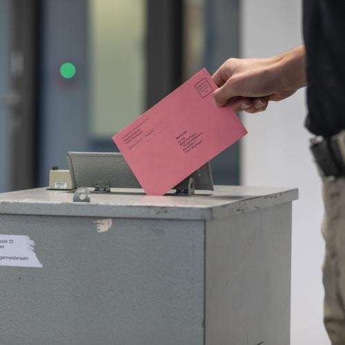 Ein Wähler wirft einen Stimmzettelumschlag in die Wahlurne